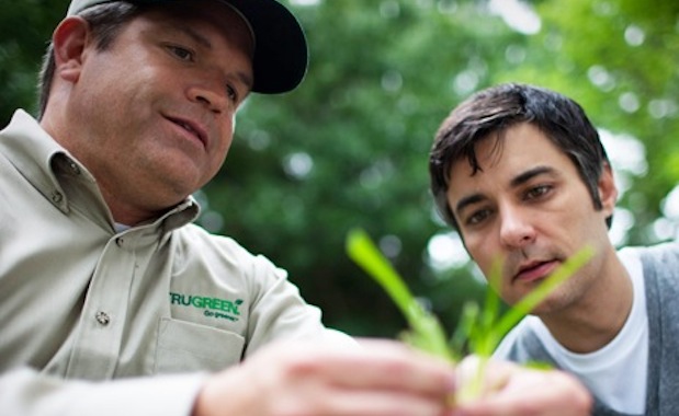TruGreen tech showing grass to a customer